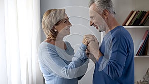 Aging man holding ladys hands, preparing to kiss them, lady being shy, coquette