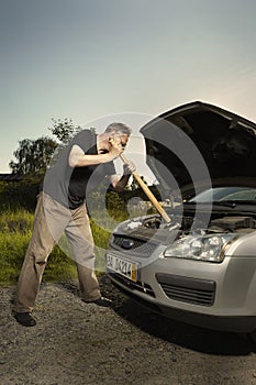 Older man alone on route checking unfunctional engine in late summer light
