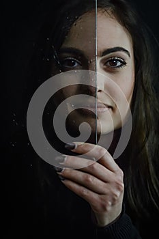 Aging Process - Beautiful long haired young woman holding a glass plate covered with droplets in front of her face, imperfections