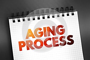 Aging process - gradual, continuous process of natural change that begins in early adulthood, text on notepad, concept background