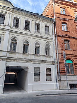 An aging white building with barred windows next to a contrasting red brick structure. The image highlights urban decay photo