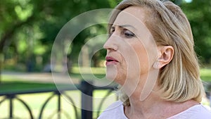 Aging woman doing breathing exercises in park, active lifestyle, healthcare