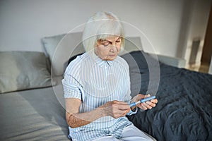 Aging woman placing a cap on top of an autoinjector