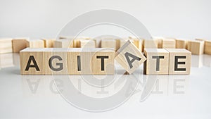 agitate text on a wooden blocks, gray background.