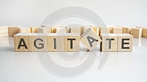 agitate text on a wooden blocks, gray background. photo