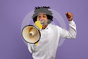 Agitated black teenager shouting into megaphone over violet studio background