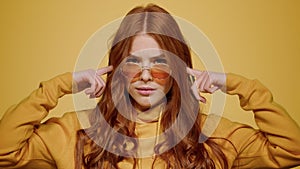 Agitated girl posing in studio. Woman closing ears on orange background