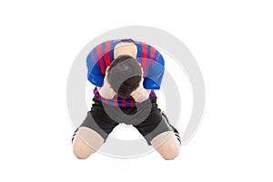 Agitated soccer player kneel down and cover his face to cry photo