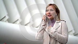 Agitated woman is calling by cell phone outdoors in city, speaking emotionally