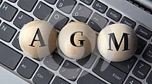 AGM - acronym on wooden balls on laptop keyboard background