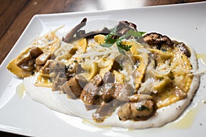 Agnolotti pasta stuffed with meet cooked with sauce and mushrooms. Traditional Italian recipe.