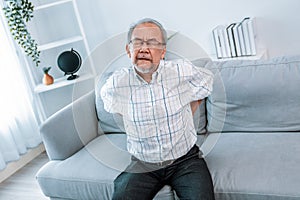 An agonizing senior man is holding his back due to back pain. photo