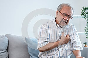 An agonizing senior man suffering from chest pain or heart attack.
