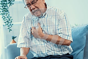 An agonizing senior man suffering from chest pain or heart attack.