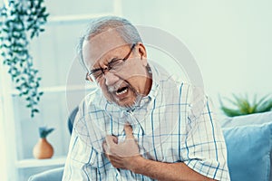 An agonizing senior man suffering from chest pain or heart attack.