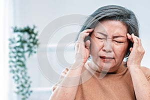 An agonizing senior woman with a headache in her contented environment.