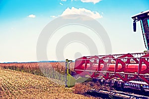 Agrarian industrial landscape with aggregates of a combine close-up, which collects a harvest on a field in a sunny day.