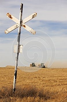 Agrarian tractors at the field with railway sign.