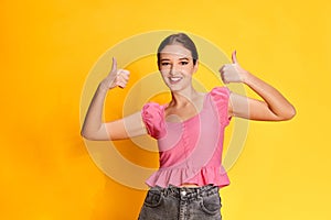 Agreement, approval. Portrait of young beautiful girl posing in pink blouse over yellow studio background. Concept of