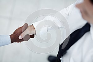 Agreement. A shot from above of a Caucasian man shaking hands with with a black businessman.