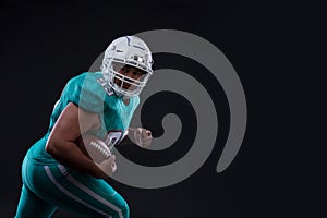 Agressive American football sportsman player on black background running in action. Sport wallpaper