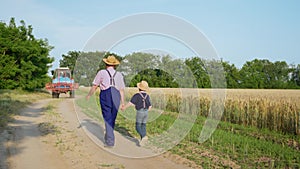 Agribusiness, elderly male farmer walks hand in hand with his grandson