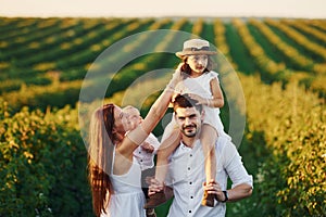 At agricultural field. Father, mother with daughter and son spending free time outdoors at sunny day time of summer