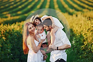 At agricultural field. Father, mother with daughter and son spending free time outdoors at sunny day time of summer