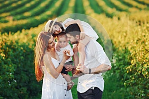 At agricultural field. Father, mother with daughter and son spending free time outdoors at sunny day time of summer