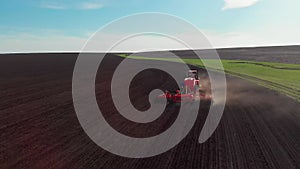 Agricultural field, landscape, red tractor plough prepares ground for planting a new crop, processing fertile soil