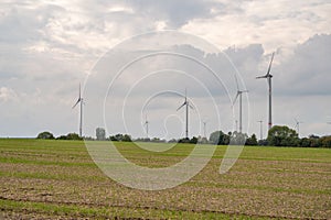 Agricultural field with wind turbines under the cloudy sky