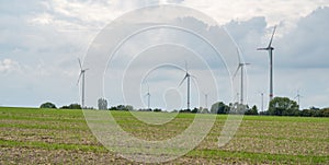Agricultural field with wind turbines under the cloudy sky