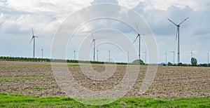 Agricultural field with wind turbines under the cloudy sky