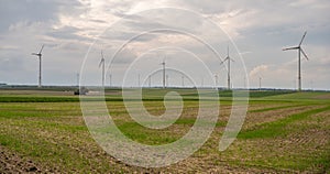 Agricultural field with wind turbines under the cloudy sky