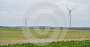 Agricultural field with wind turbines under the cloudy sky