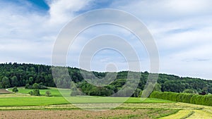 Agricultural fields with crops in the countryside in a hilly valley under a cloudy sky