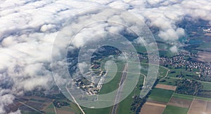 Agricultural fields and houses from above. Aerial view out of an airplane window.