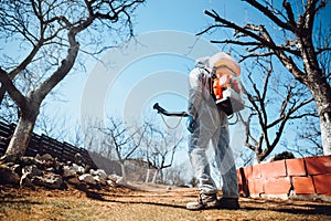 Agricultural industrial details farmer using sprayer machine for pesticide control in fruit orchard during spring time
