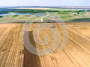 Agricultural land after harvest crop, aerial view at wheat field, farm machinery and green lands