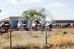 Agricultural machinery, harvesters, harrows are behind the fence