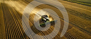 The agricultural machinery harvesting crops in a vast golden field at sunset. AI generated image photo