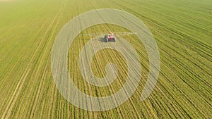 Agricultural machinery sprays mineral fertilizer on a green field, natural, spring background