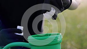 Agricultural seasonal work. Unrecognisable farmer in garden gloves adds, mixes pesticide, herbicide for protecting