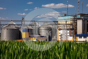 Agricultural Silos on the background of the field. Storage and drying of grains, wheat, corn, soy, sunflower against the blue sky