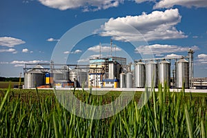 Agricultural Silos on the background of the field. Storage and drying of grains, wheat, corn, soy, sunflower against the blue sky