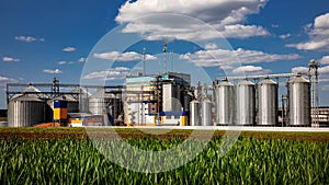 Agricultural Silos on the background of the field. Storage and drying of grains, wheat, corn, soy, sunflower against the blue sky