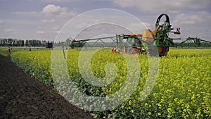 Agricultural sprayer detail. Flowering rapeseed field. Working spraying machine in yellow canola land. Spring landscape