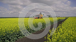 Agricultural sprayer detail. Flowering rapeseed field. Working spraying machine in yellow canola land. Spring landscape