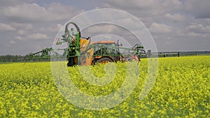 Agricultural sprayer detail. Flowering rapeseed field. Working spraying machine in yellow canola land. Spring landscape