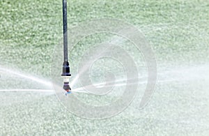 Agricultural sprinkler head close up, spraying fingers of water.